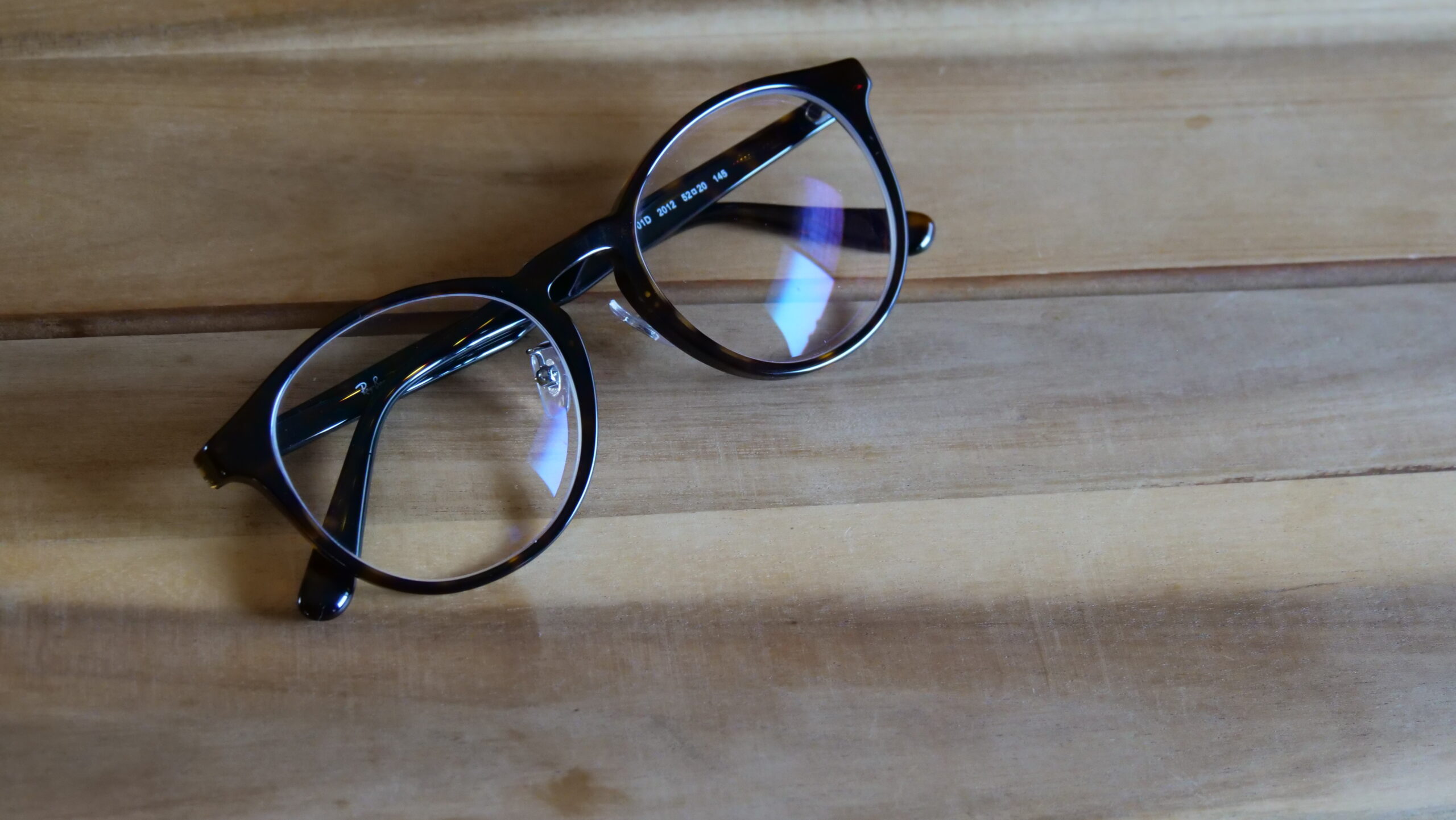 木目の机の上に置かれている茶色のボストン型のおしゃれな眼鏡の画像