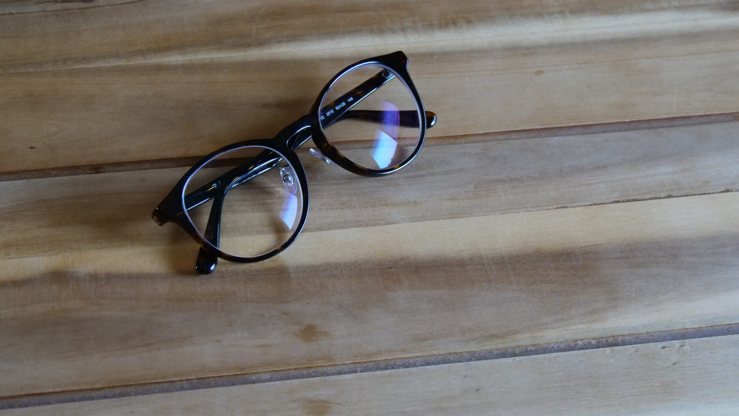 木目の机の上に置かれているボストン型のおしゃれな眼鏡の画像