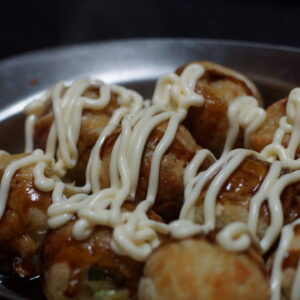 たこ焼きを銀の皿に乗せいている写真