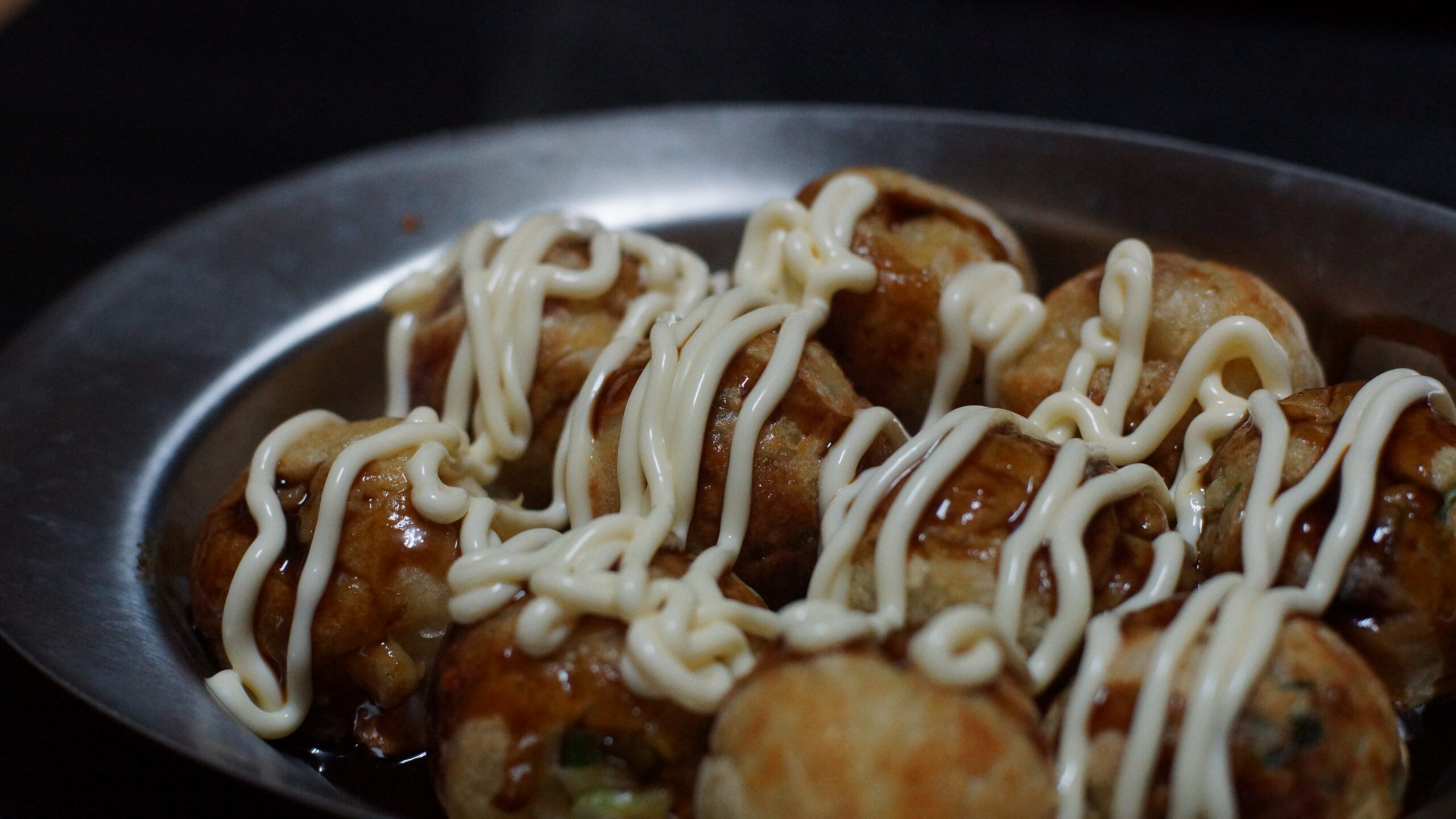 たこ焼きを銀の皿に乗せいている写真