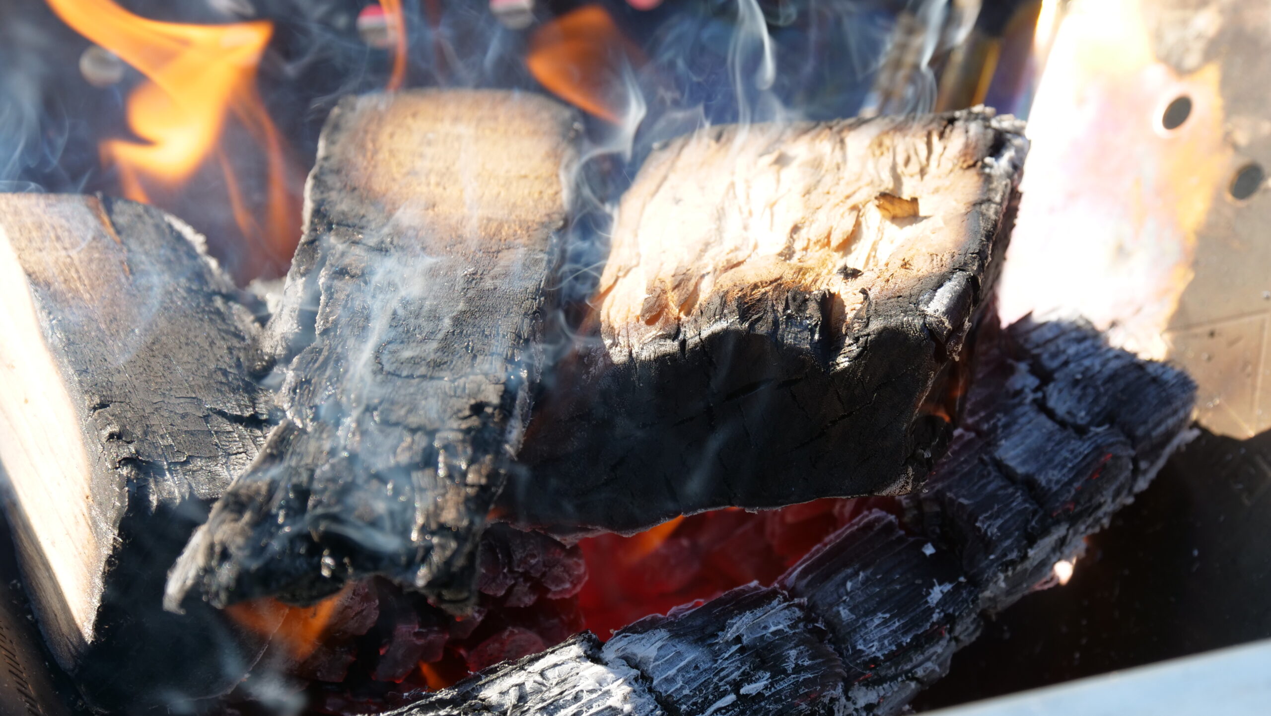 木材を燃やす焚火をしていて炎が出て木材が焦げている写真