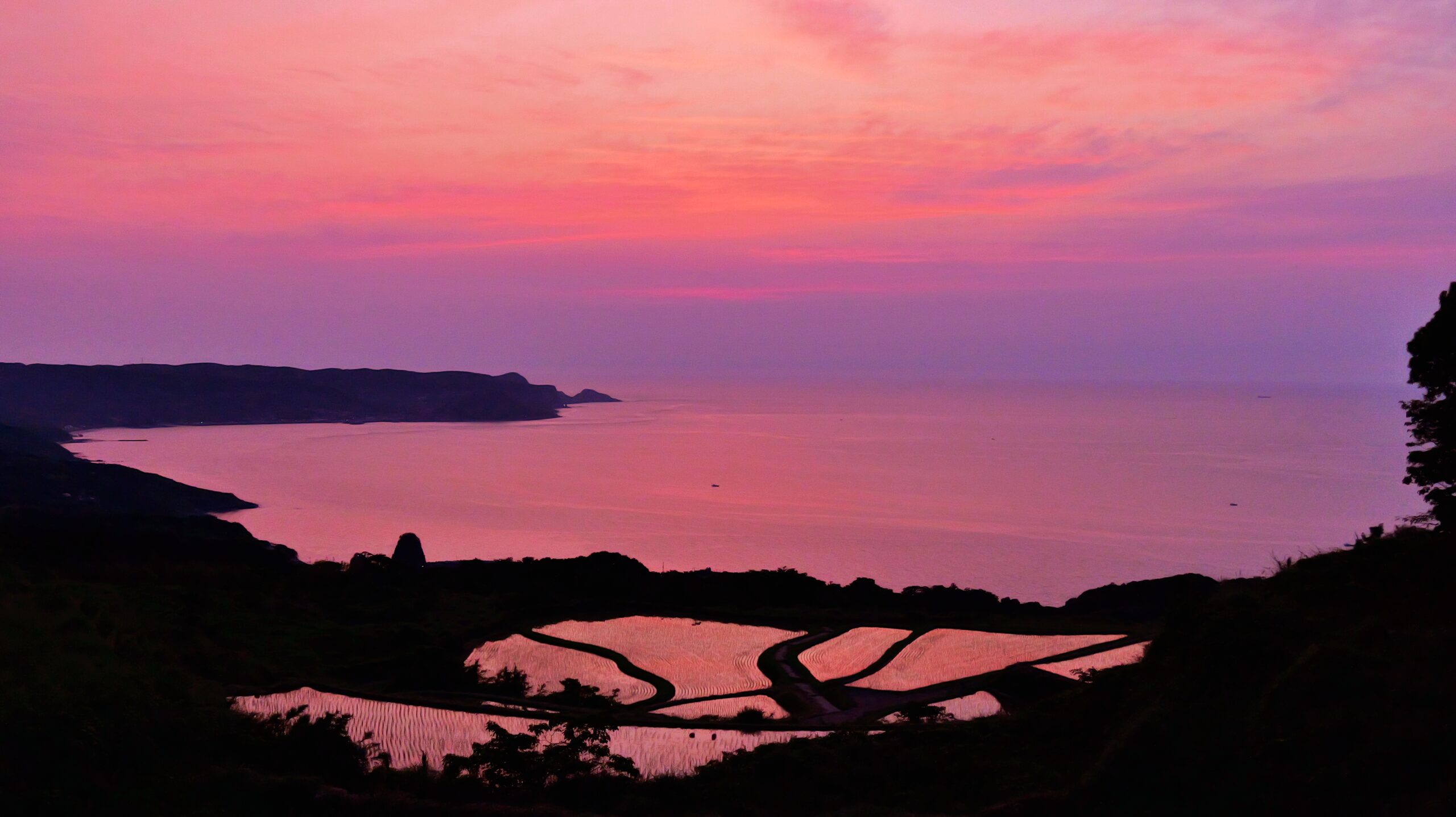 夕焼けの棚田に赤い空が反射している写真