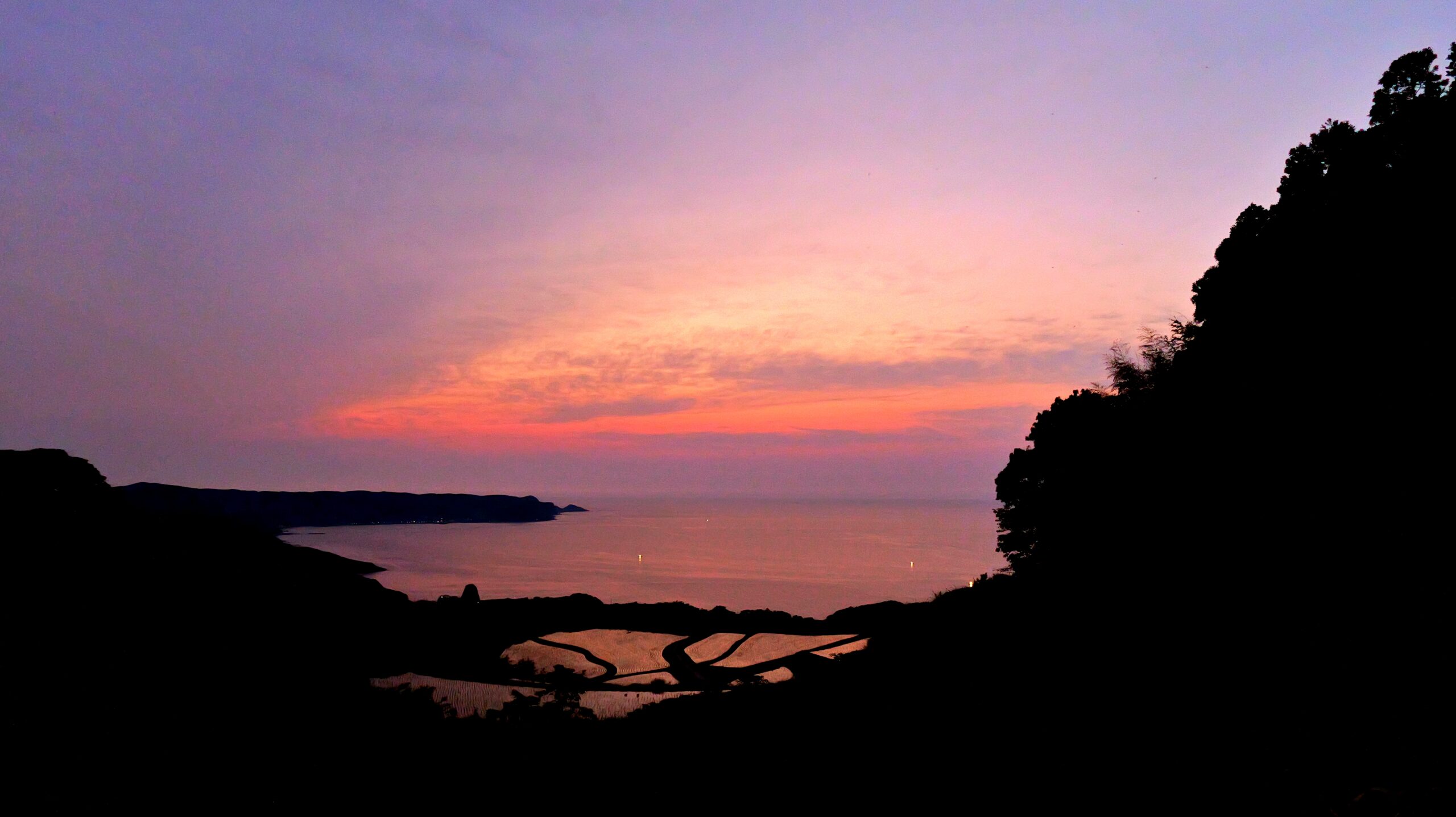 夕焼けの棚田に赤い空が反射しているヒキの写真