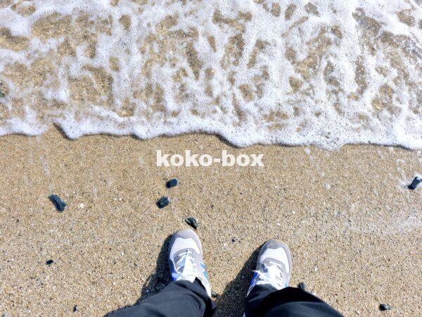 波打ち際に立つ人の足が写った波の写真