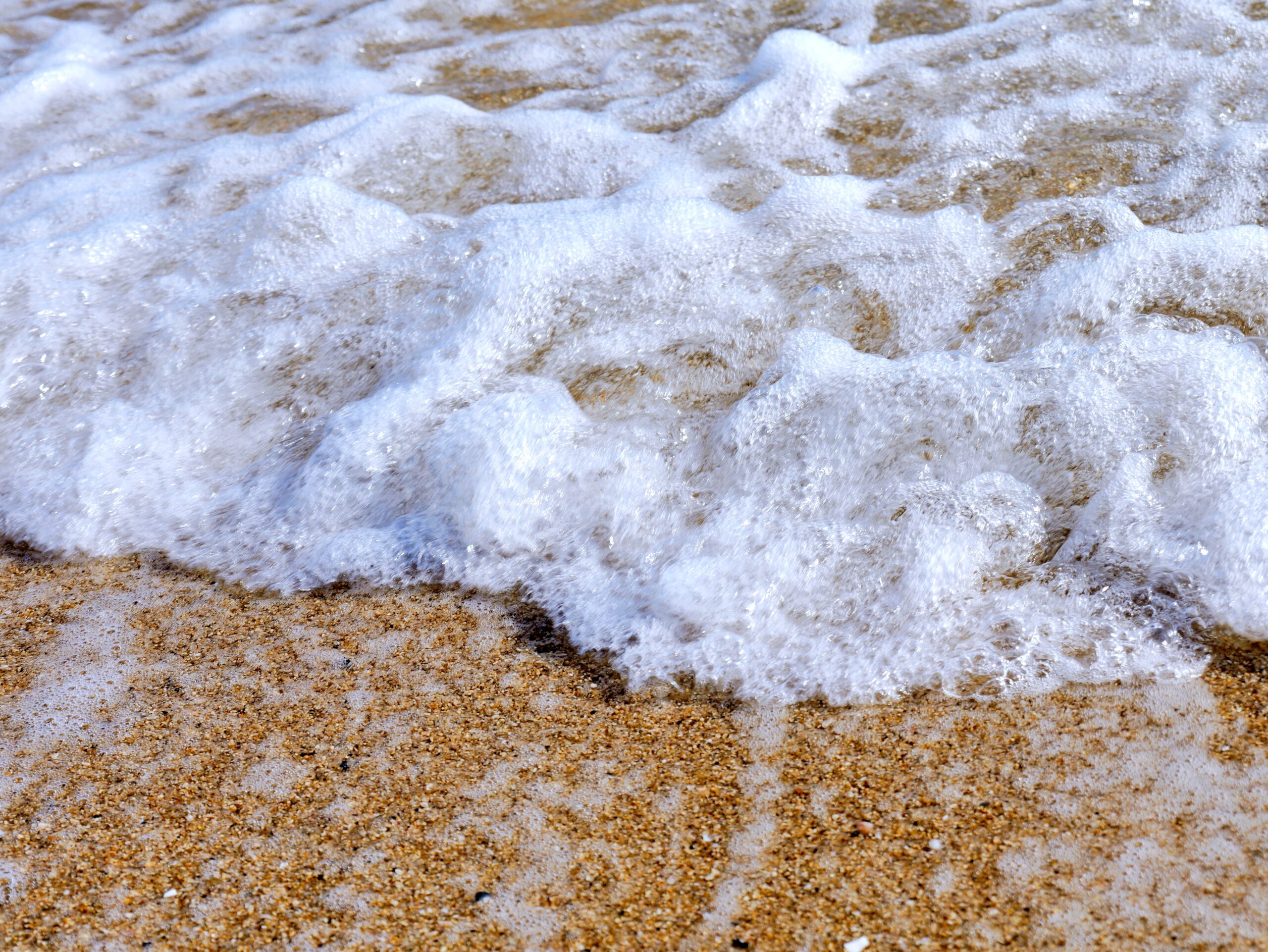 綺麗な砂浜に打ち寄せる波の躍動感のあるアップの写真