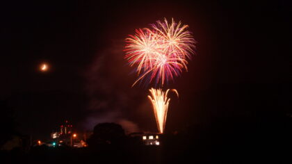 3つの打ちあがった綺麗な花火と半月のコラボの写真