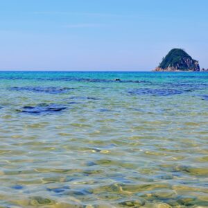 青い空と透き通るような海と島が写った海岸の写真