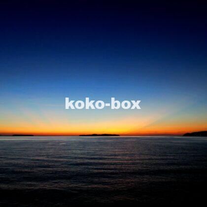 水平線と島から伸びる赤とオレンジの幻想的な射線が綺麗なグラデーションの夕焼けの写真
