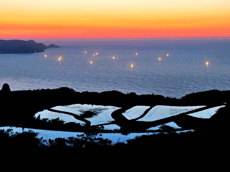 夕暮れの棚田と海に浮かぶ漁火 横位置 写真素材