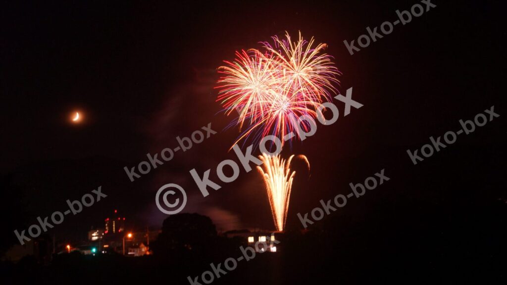3つの打ち上げ花火と半月の夜景写真素材