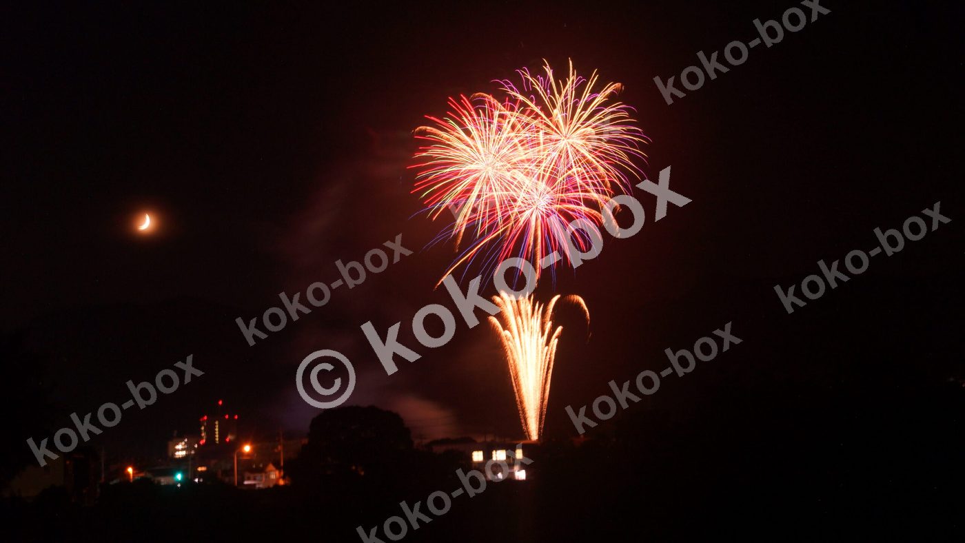 3つの打ち上げ花火と半月の夜景写真素材