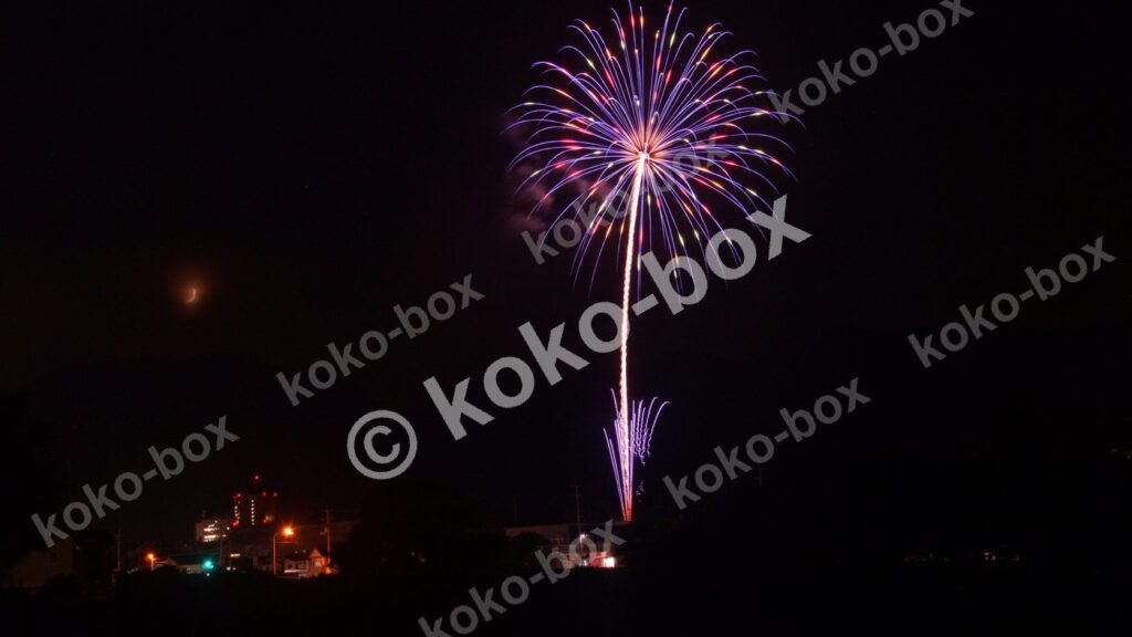 紫色の花火と半月の夜景コラボ写真素材