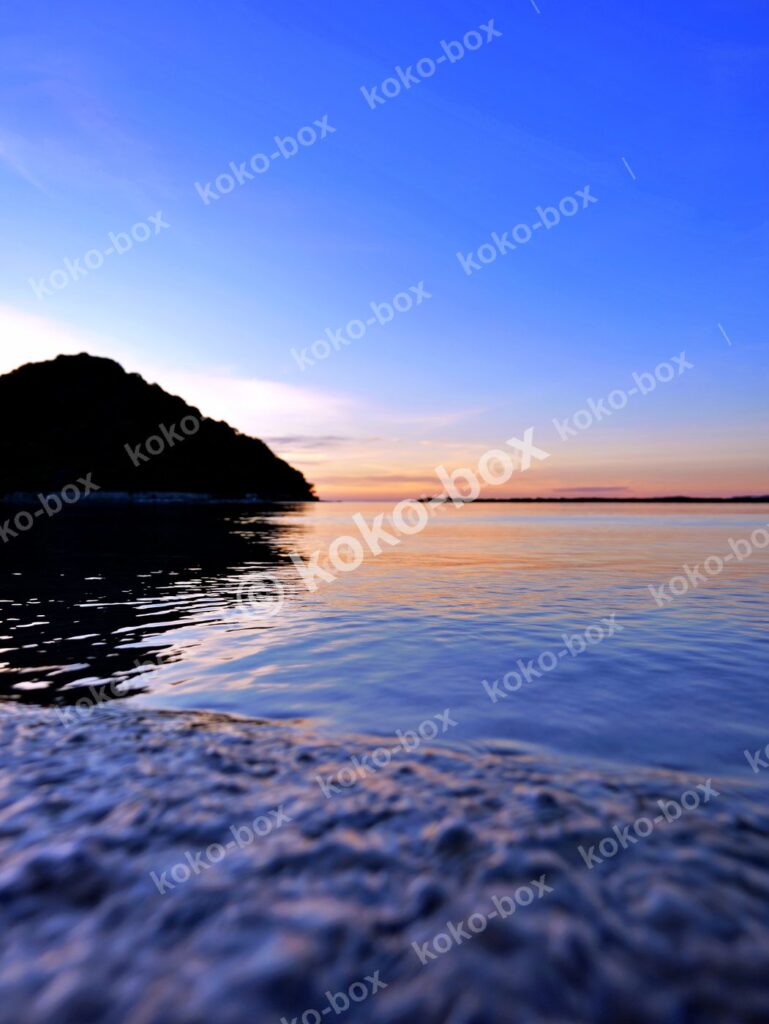 夕暮れの海辺と島のシルエット 縦位置写真素材