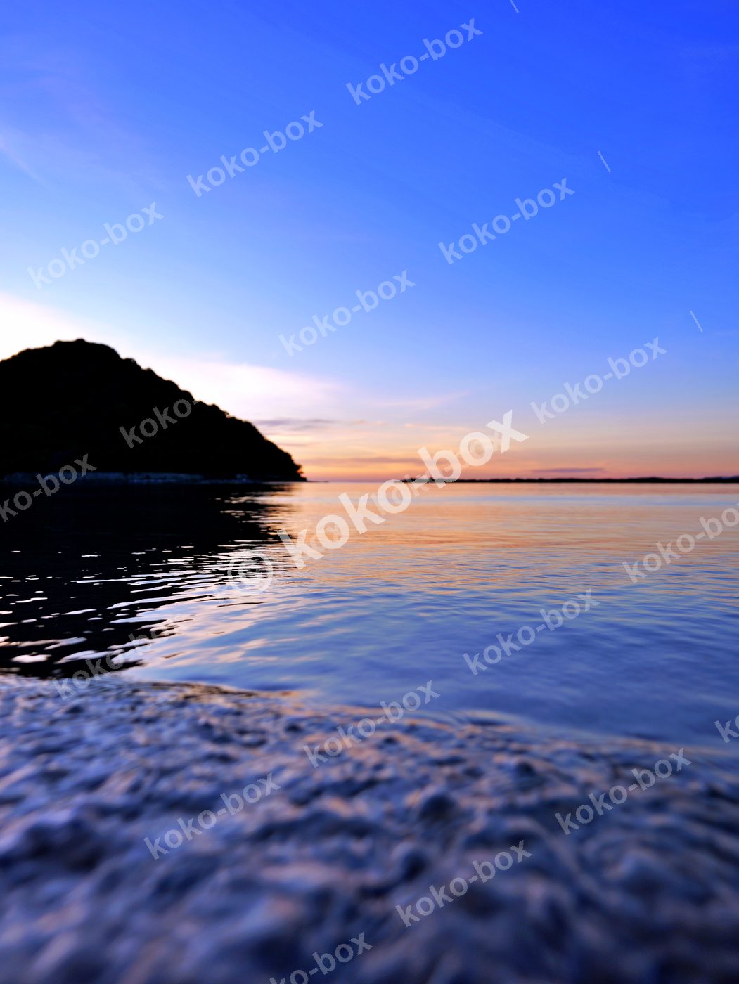 夕暮れの海辺と島のシルエット 縦位置写真素材
