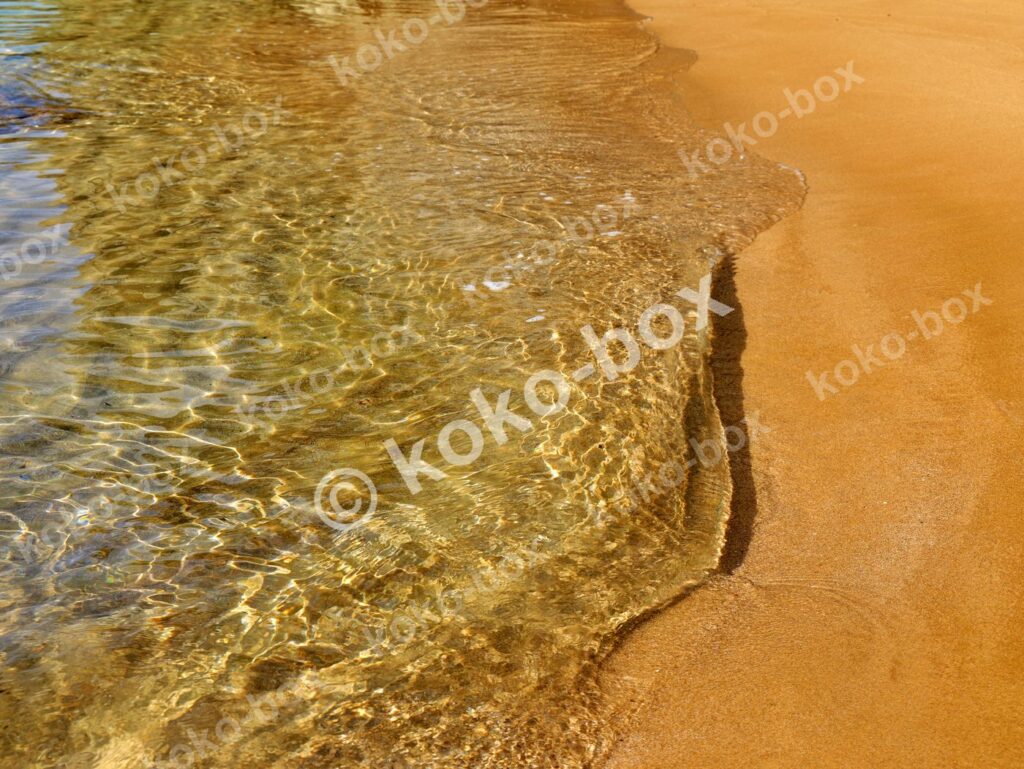 澄んだ波打ち際と金色砂浜 横位置 写真素材