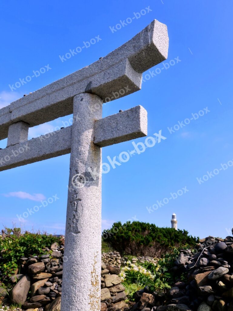 海辺の石鳥居と遠くの灯台 縦位置写真
