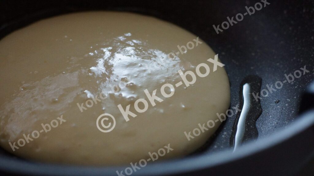 フライパンでホットケーキを調理する写真 横位置 写真素材