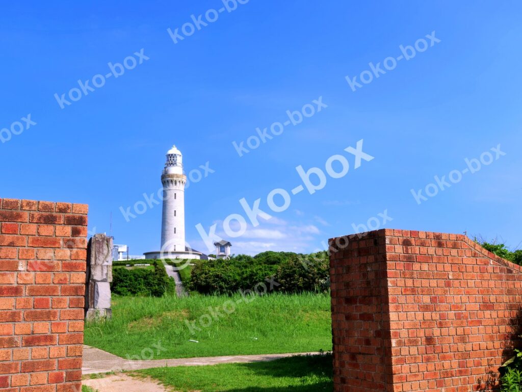 青空と白い灯台、手前の赤煉瓦のゲート 横位置写真