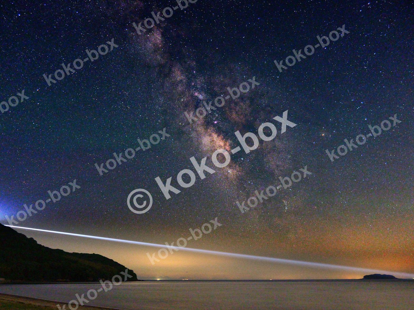 天の川と海辺を照らす光の筋 横位置 写真素材