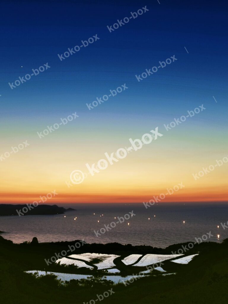 夕暮れの海と棚田 幻想的な縦位置写真素材