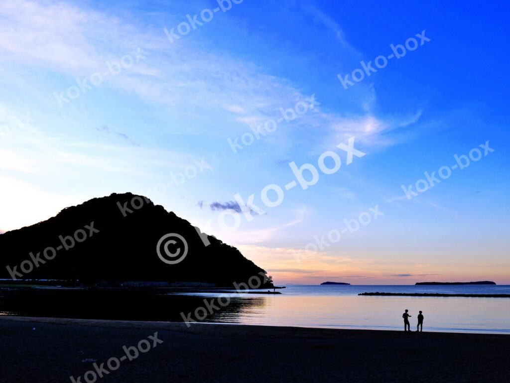 夕暮れの海辺と寄り添う二人 横位置 写真素材