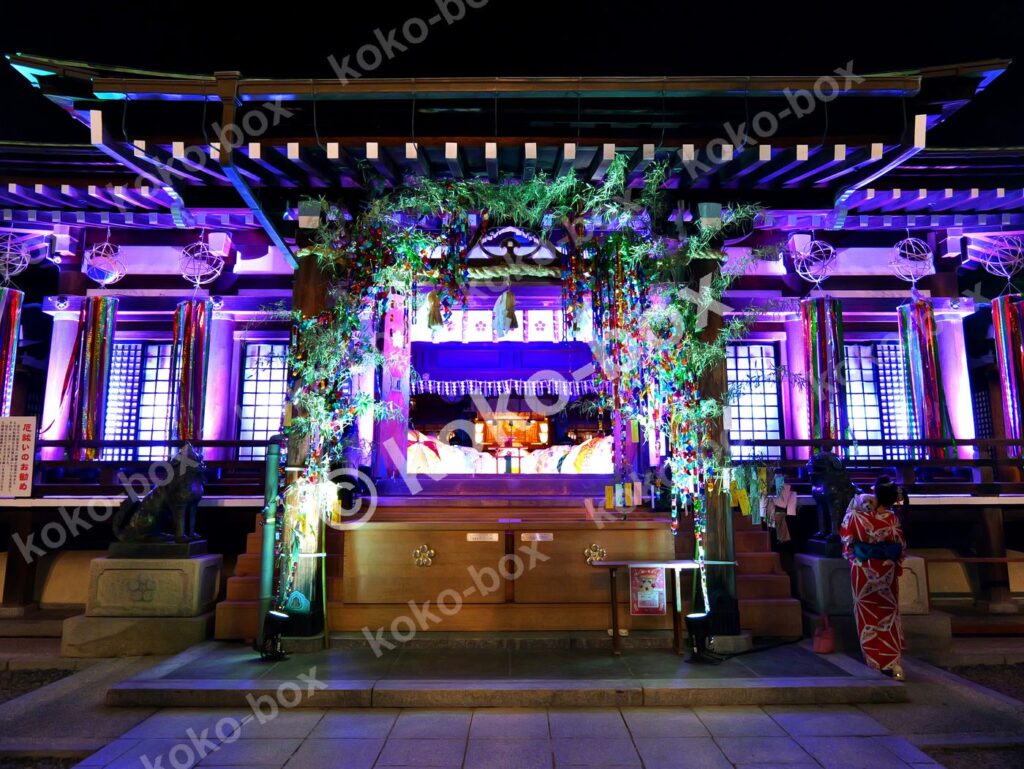 ライトアップされた夜の神社七夕飾りと女性 横位置