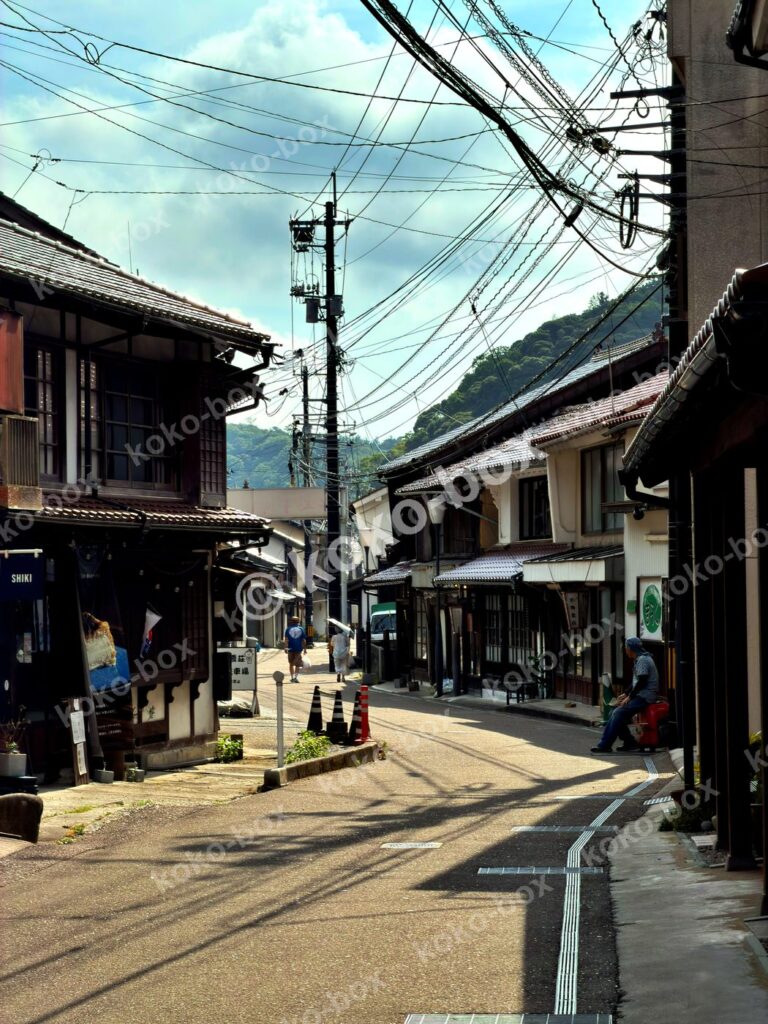 日本の古い町並みを歩く人と石畳の路地の縦位置写真