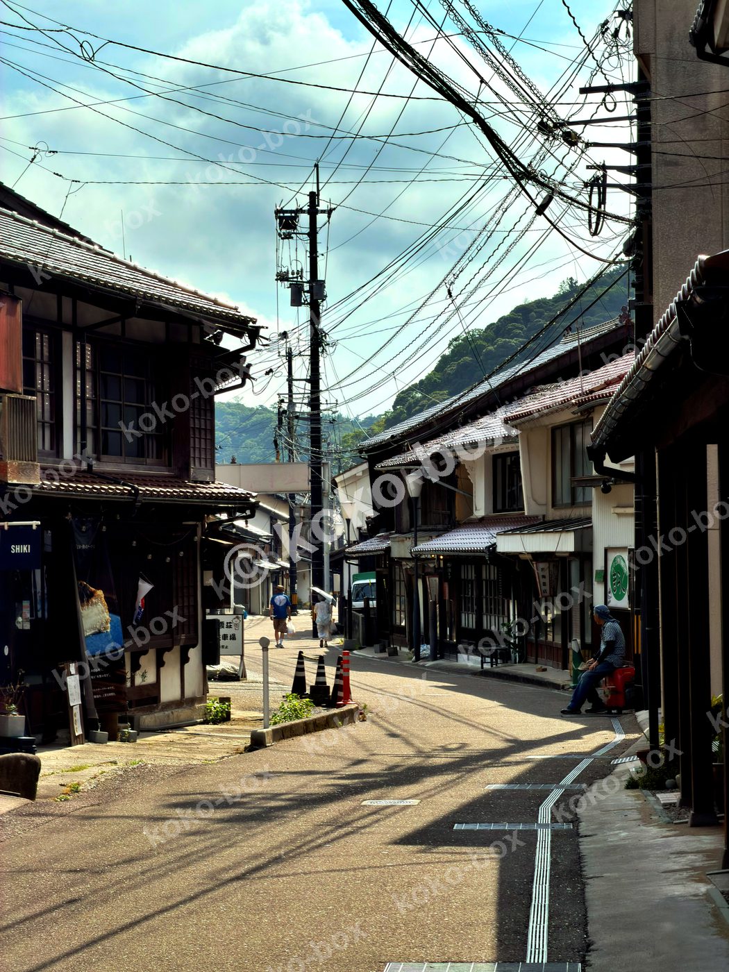 日本の古い町並みを歩く人と石畳の路地の縦位置写真