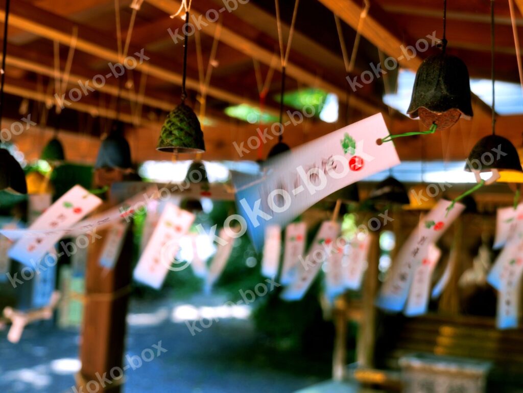 神社の軒先に吊るされた風鈴と揺れる短冊の横位置写真