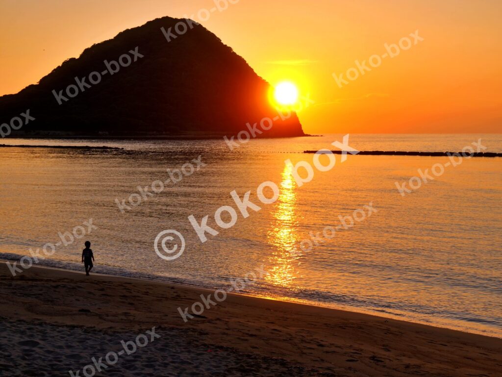 夕暮れの海岸を歩く子供のシルエット 横位置