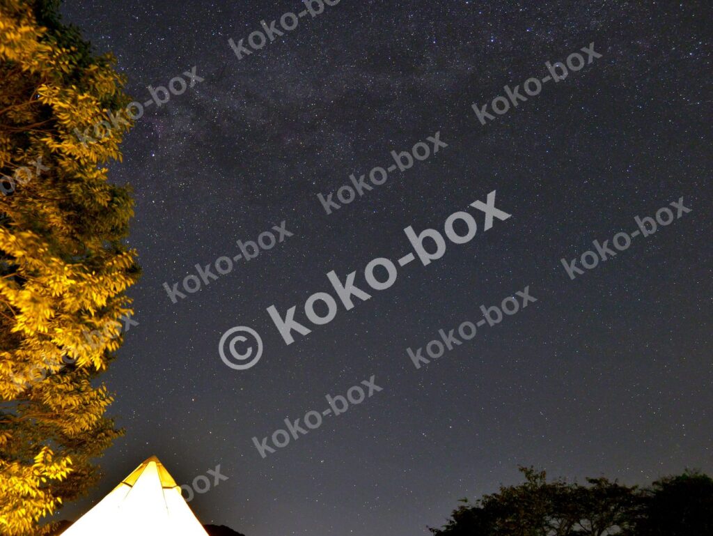 満天の星空の下で暖かく光るテントの横位置写真