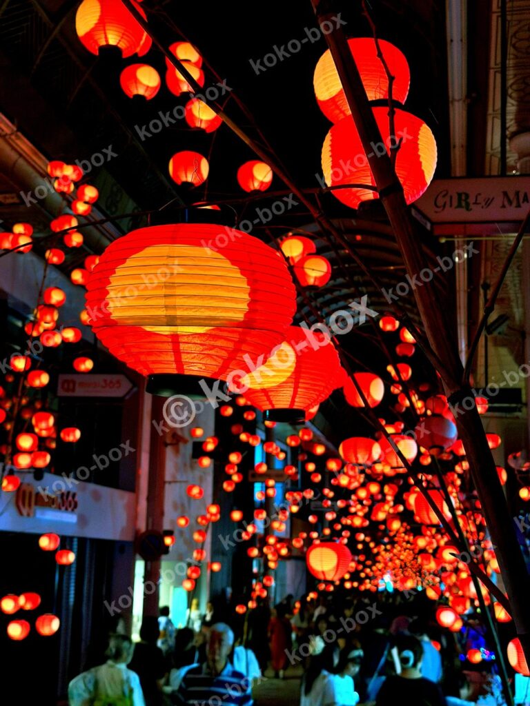 夜の商店街に飾られた無数の赤い和提灯の縦位置写真